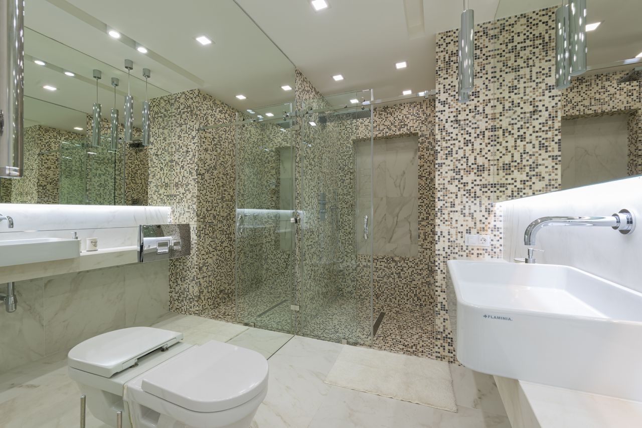 Mastering the First Impression: Your intriguing post title goes here A sleek and spacious modern bathroom featuring elegant mosaic tiles and a glass shower.