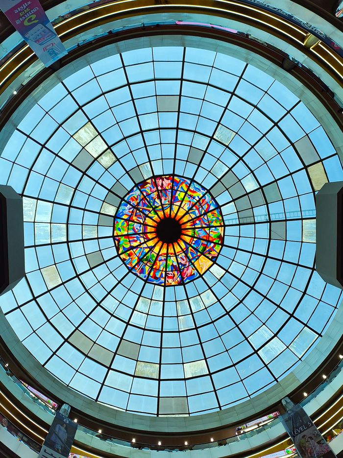 service-01 Colorful stained glass ceiling dome in a shopping mall, showcasing vibrant art.