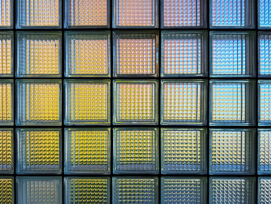 about-01 Glass block window-wall with rainbow colors of autumn leaves and sky in the background.